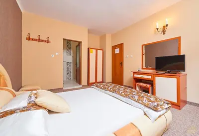 a large bedroom with a large bed and a television at Peneka Hotel in Pomorie