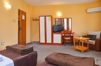 a room with a living room with a television and a desk at Peneka Hotel in Pomorie