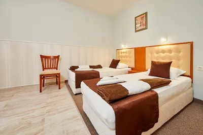 a hotel room with two beds and a chair at Peneka Hotel in Pomorie