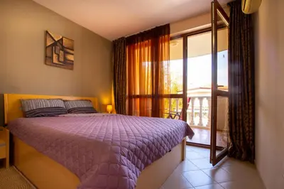 a bedroom with a purple bed and a window at Kalia apartment in Sunny Beach