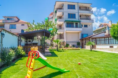 a playground in a yard in front of a building at Chrystal Guest House in Obzor