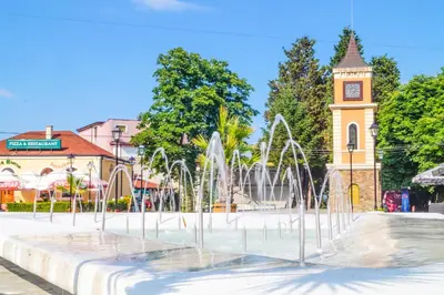 a fountain in front of a building with a clock tower at Chrystal Guest House in Obzor