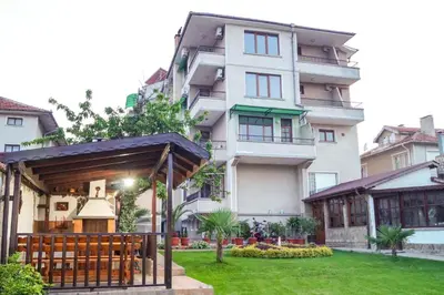 a large white building with a green yard at Chrystal Guest House in Obzor