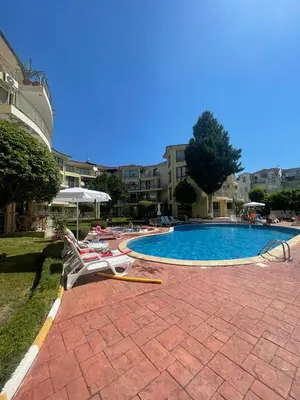 a swimming pool with lounge chairs next to a building at Aurelia Residences in Ravda