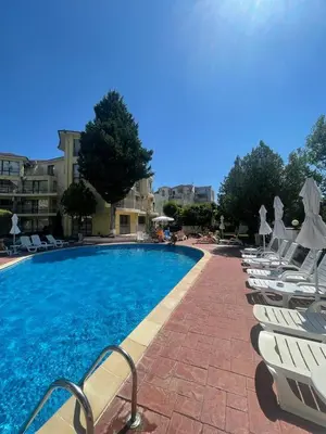 a swimming pool with white lounge chairs next to a building at Aurelia Residences in Ravda