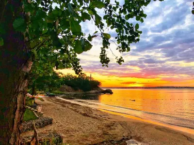a view of a beach with a sunset in the background at Marina Sun Sea View Apartment in Sozopol
