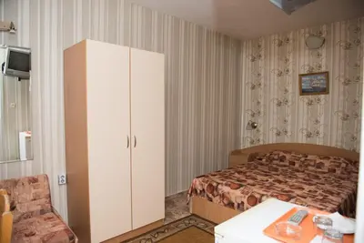 a bedroom with a bed and a cabinet and a table at Стаи за гости in Varna City