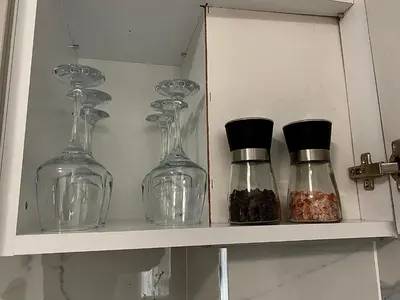 three glass bottles on a shelf in a cabinet at AVRORA SUITE in Varna City
