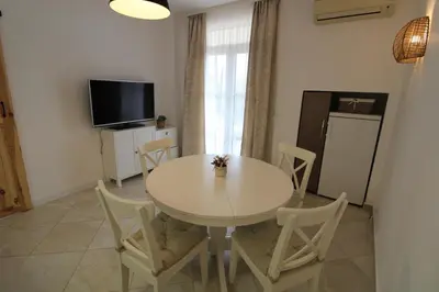 a dining room with a white table and chairs at Flores Garden - Menada Apartments in Chernomorets