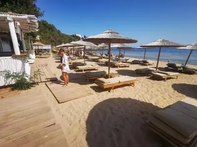 a man standing on a beach with chairs and umbrellas at Flores Garden - Menada Apartments in Chernomorets