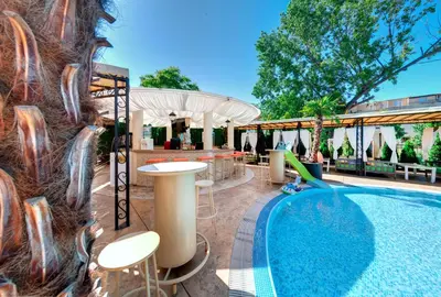 a pool at a resort with tables and chairs at Avenue Deluxe Hotel in Sunny Beach