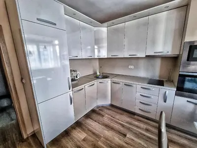 a kitchen with white cabinets and wooden floors at Sea Light in Burgas City