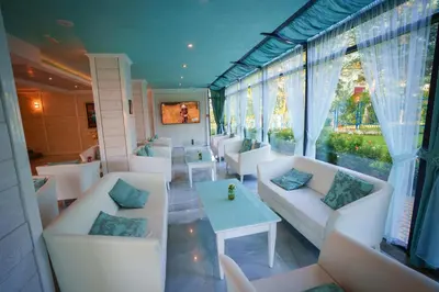 a room with white couches and a table and windows at Perla Royal Hotel - All Inclusive in Primorsko