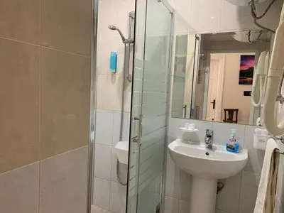 a bathroom with a sink and a shower with a mirror at Guest Rooms Donovi in Varna City