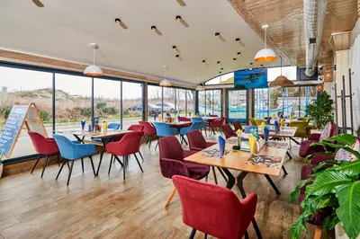 a restaurant with tables and chairs and windows at Petar and Pavel Hotel & Relax Center in Pomorie