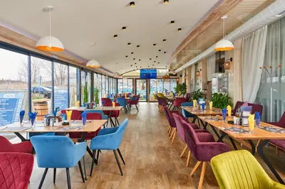 a restaurant with tables and chairs and windows at Petar and Pavel Hotel & Relax Center in Pomorie