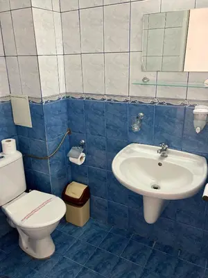 a blue tiled bathroom with a toilet and a sink at Plovdiv Hotel in Primorsko