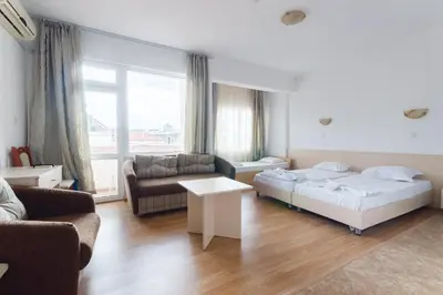 a bedroom with a bed and a couch and a table at Plovdiv Hotel in Primorsko