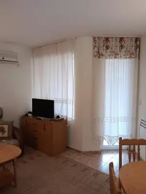 a living room with a television on a dresser and a window at Rutland Bay in Ravda