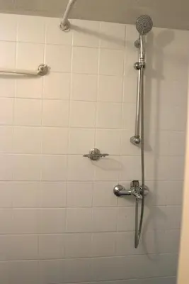 a shower in a bathroom with a white tiled wall at Cozy Nest Charming Loft in the heart of Varna in Varna City