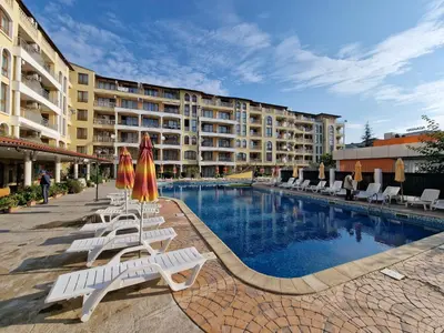 a pool with chairs and umbrellas next to a building at Menada Royal Dreams Apartments in Sunny Beach