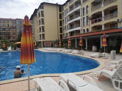 a large swimming pool with chairs and an umbrella at Menada Royal Dreams Apartments in Sunny Beach