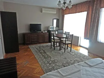 a living room with a table and chairs and a television at Guest Rooms Casa Luba in Sveti Vlas
