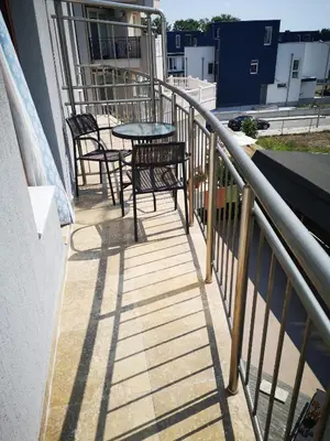 a balcony with chairs and a table on a building at Guest House Petrovi in Ravda