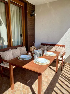 a wooden table with plates and glasses on it at AJ Apartment 2, Santa Marina Holiday Village, Sozopol in Sozopol