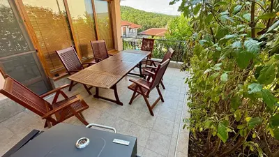 a patio with a table and chairs and a grill at Guest House Primorsko - Uzundzha in Primorsko