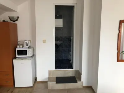 a small kitchen with a microwave and a bathroom at Guest House Liliya in Sozopol