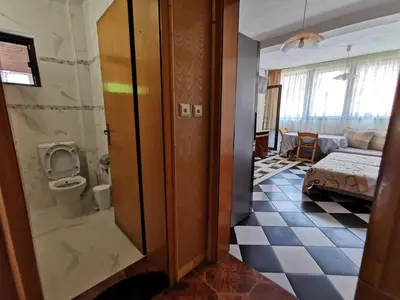 a room with a bathroom with a toilet and a bedroom at Guest House Liliya in Sozopol