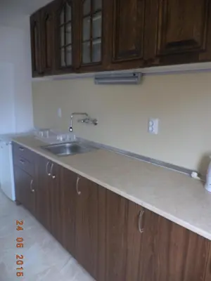 a kitchen with a sink and wooden cabinets at Guest House Liliya in Sozopol