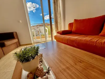 a living room with a couch and a plant on the floor at Two-bed flat in Sunny Beach with pool view in Sunny Beach