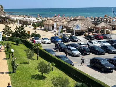 a parking lot with cars parked in front of the beach at Phoenix APARTMENT Апартамент Феникс in Sveti Vlas