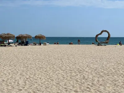 a beach with chairs and umbrellas and the ocean at Phoenix APARTMENT Апартамент Феникс in Sveti Vlas