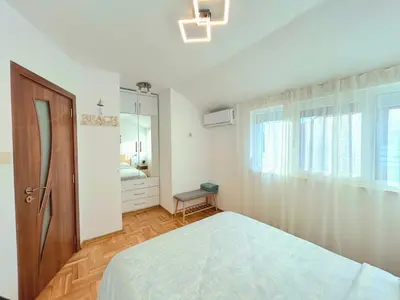a white bedroom with a bed and a mirror at Centro apart in Burgas City