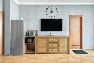 a kitchen with a refrigerator and a tv on a wall at Paradise Apartments Primorsko in Primorsko