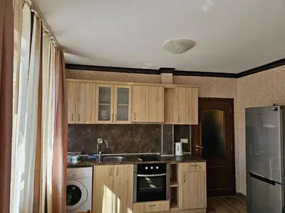 a kitchen with wooden cabinets and a sink and a refrigerator at Apartament Marinela 2 in Pomorie