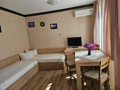 a room with two beds and a table and a television at Apartament Marinela 2 in Pomorie