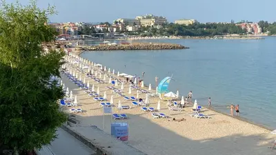 a beach with chairs and umbrellas and people on it at Bellevue Beachfront Paradise in Ravda