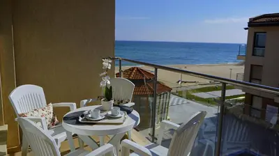 a table and chairs on a balcony with the beach at Апартаменти Обзор Бийч - Apartments Obzor Beach in Obzor