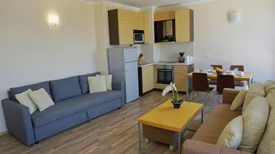 a living room with a blue couch and a kitchen at Апартаменти Обзор Бийч - Apartments Obzor Beach in Obzor
