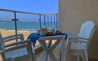 a table with a plate of food and a view of the beach at Апартаменти Обзор Бийч - Apartments Obzor Beach in Obzor