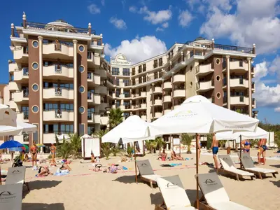 a beach with chairs and umbrellas in front of a hotel at Hotel Golden Ina - All Inclusive - Beachfront in Sunny Beach