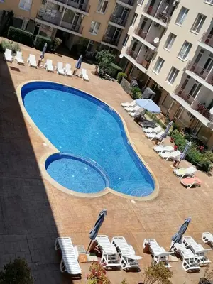 a large swimming pool with chairs and lawn chairs at Апартамент Александър in Sunny Beach