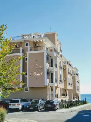 a large building with cars parked in front of it at Mary Beach Resort Premium Apartments in Sveti Vlas