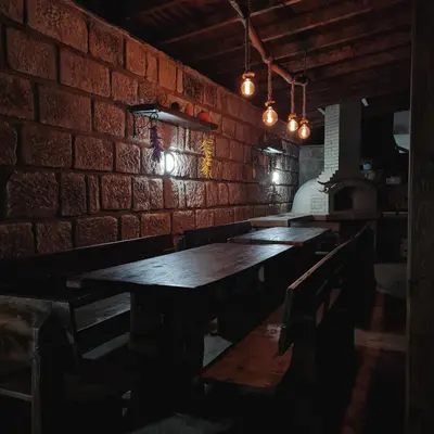 a room with a brick wall and wooden tables and chairs at Eco Lodge St Ignatius Еко лодж Игнажден in Debelets
