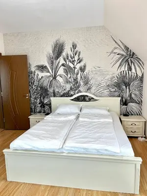 a white bed in a bedroom with plants on the wall at Golden Hermes Apartments in Sunny Beach