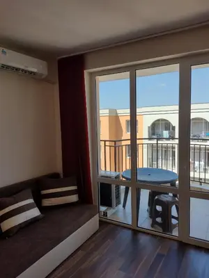 a room with a balcony with a couch and a table at Ред хаус in Sunny Beach